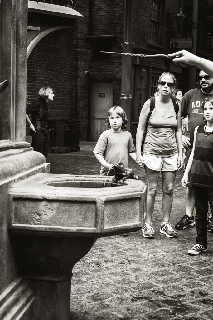 Onlookers fascinated by a person controlling the fountain with her wand at Diagon Alley